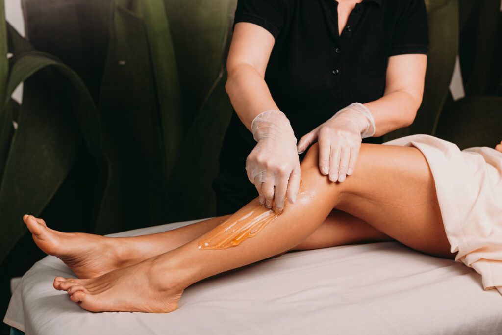 Caucasian lady with beautiful legs is having a sugar epilation during a professional spa procedure